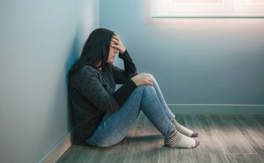 Depresyonda olan, eli yüzü yerde oturan bir kadın.