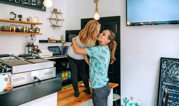Мать целует свою дочь во время работы в кофейне — стоковое фото