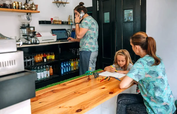 Mère dessin avec sa fille tandis que le père travaille dans leur propre café — Photo