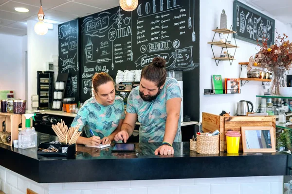 Omistajat kahvila työskentelevät tarkastellaan tabletin — kuvapankkivalokuva