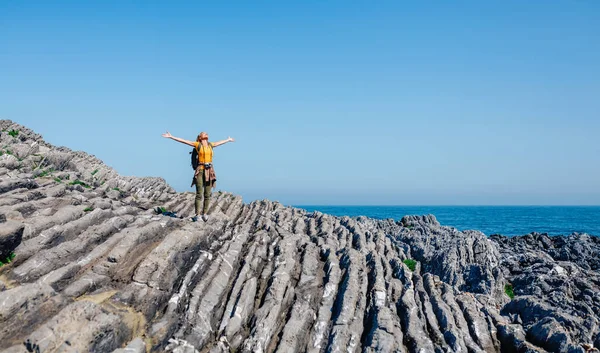 Jeune femme levant les bras randonnée à travers le paysage rocheux flysch — Photo
