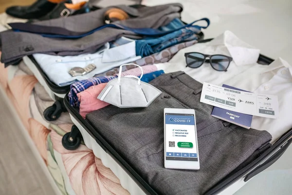 Maleta de hombre de negocios preparada para viaje de negocios con pasaporte covid en el móvil — Foto de Stock