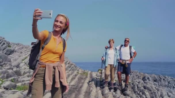 Jovem mulher tomando selfie com móvel para seus pais através de flysch rock — Vídeo de Stock