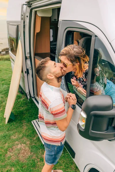 Casal beijando através da janela van campista durante uma viagem — Fotografia de Stock