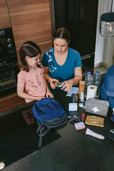 Madre preparando mochila de emergencia con su hija — Foto de Stock