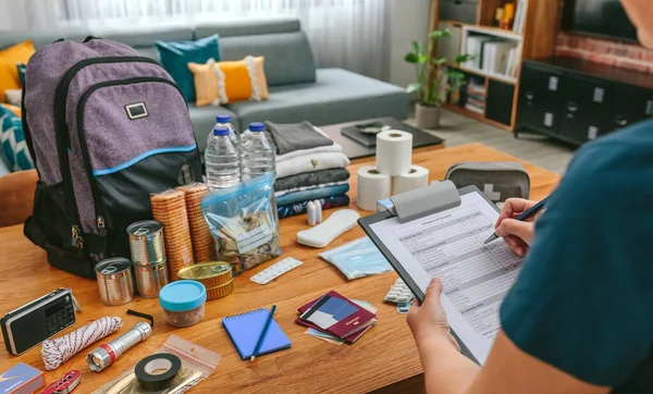 Mulher fazendo checklist de mochila de emergência — Fotografia de Stock