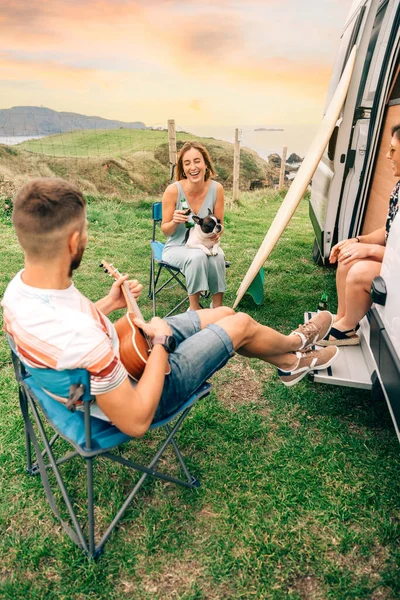 Amigos com seu cão bebendo cerveja na frente de sua van campista — Fotografia de Stock