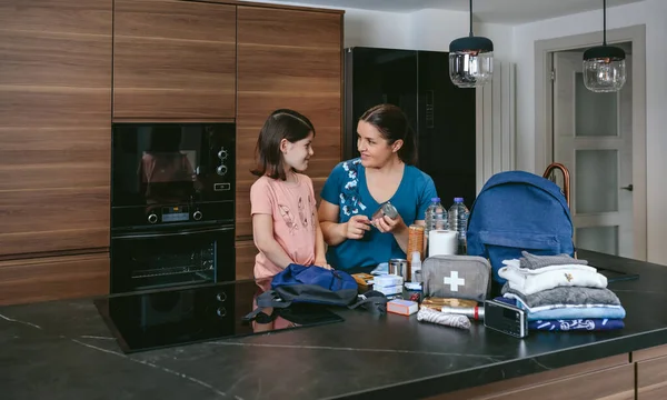 Madre explicando a su hija cómo preparar la mochila de emergencia —  Fotos de Stock