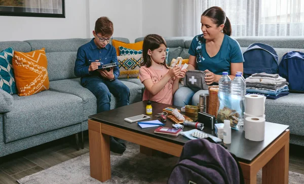 Mother preparing emergency backpack with her children — Stock Photo, Image