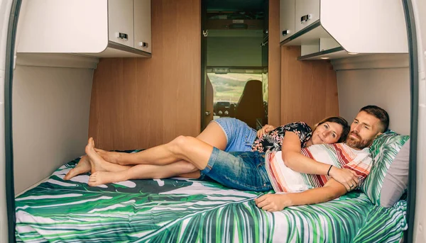 Casal descansando abraçado na cama de sua van campista com pernas entrelaçadas — Fotografia de Stock