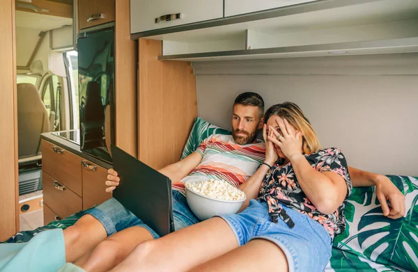 Jeune couple regardant un film d'horreur sur la tablette couchée sur le lit de leur camping-car. — Photo