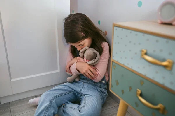 Infeliz chica abrazando peluche sentado en el suelo — Foto de Stock