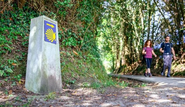 Signpost of Saint James way with pilgrims walking — Stock Photo, Image