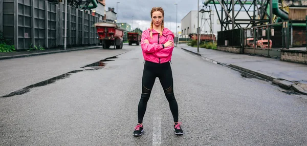 Wanita sporty melihat kamera berpose di depan pabrik — Stok Foto