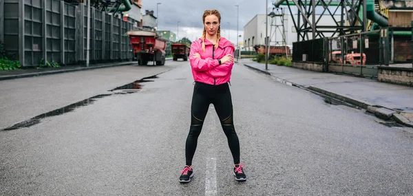 Femme sportive regardant caméra posant devant une usine — Photo