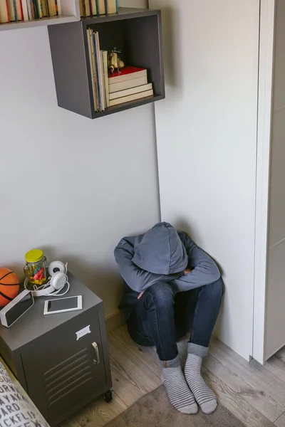 Adolescente niño con ansiedad sentado en el suelo de su dormitorio con la cabeza inclinada —  Fotos de Stock