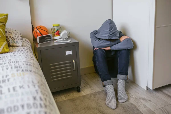 Ragazzo adolescente con ansia seduto sul pavimento della sua camera da letto con la testa a riposo — Foto Stock
