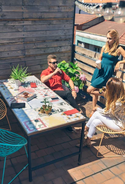 Groupe d'amis discutant et buvant lors d'une fête sur une terrasse — Photo