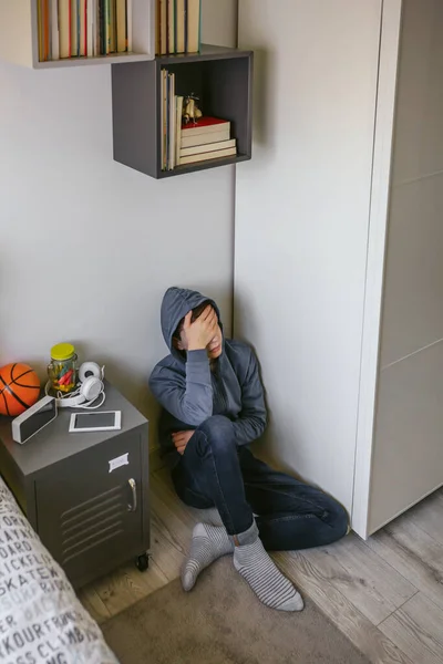 Deprimido adolescente masculino sentado en el suelo en su dormitorio —  Fotos de Stock
