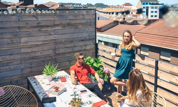 Groupe d'amis discutant et buvant lors d'une fête sur une terrasse — Photo