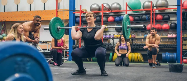 Spor arkadaşları ona tezahürat yaparken kadın halter kaldırıyor. — Stok fotoğraf