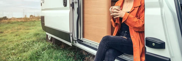 Mulher bebendo café sentado à porta de uma campervan — Fotografia de Stock
