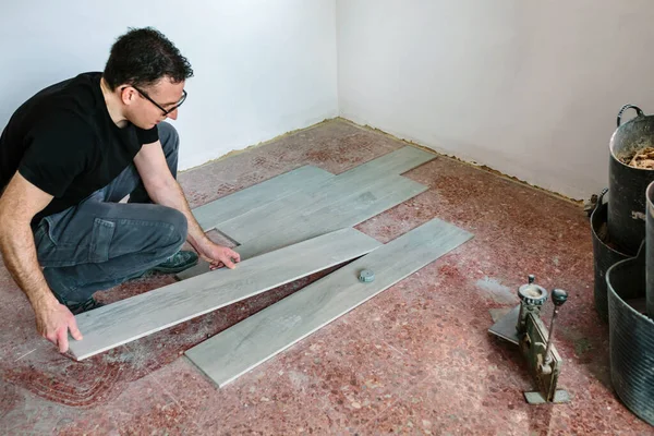 Maurer verlegt Fliesen, um einen Fußboden zu verlegen — Stockfoto