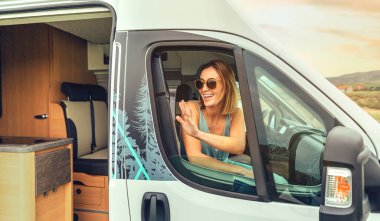 Kamp arabasında oturan güneş gözlüklü genç kadın.