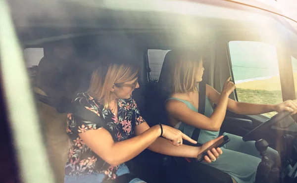 Women searching direction in smartphone while traveling in caravan — ストック写真