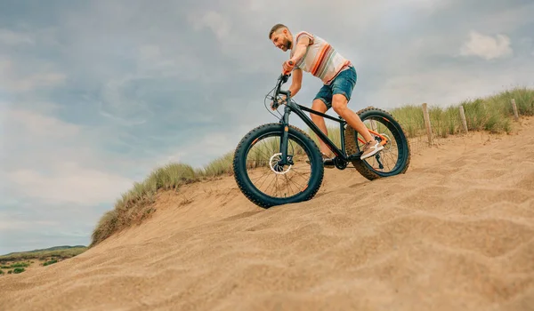 Man riding a fat bike through the beach dunes — Stock Photo, Image