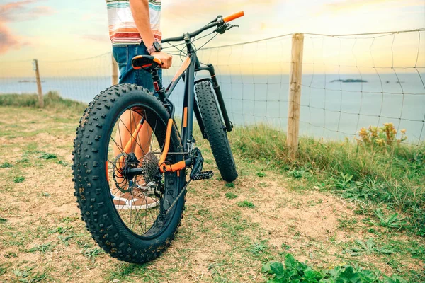 Bicicleta gorda en la playa con un tipo sosteniéndola — Foto de Stock