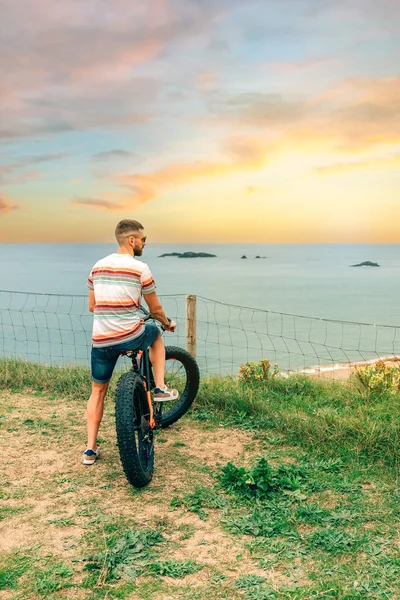 Man riding a fat bike looking at the sea from the coast — Stock Photo, Image