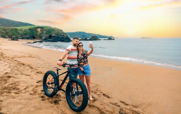 ビーチで携帯電話で自転車を取る脂肪の多いカップル — ストック写真