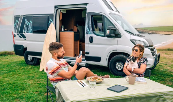 若いです男取る写真に幸せな女性巨大可愛いです犬とともにCamper Vanとビーチ上の背景 — ストック写真