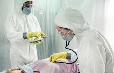 Bir sahra hastanesindeki doktorlar koronavirüs hastasını muayene ediyor ve gözetiyorlar.