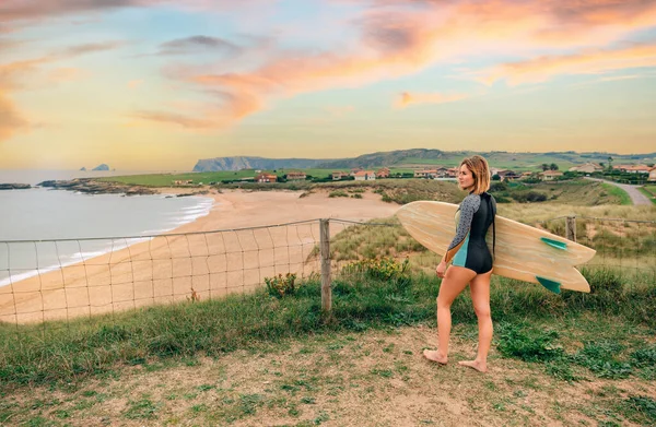 穿着泳衣和冲浪板的年轻冲浪女子从岸边看海滩 — 图库照片