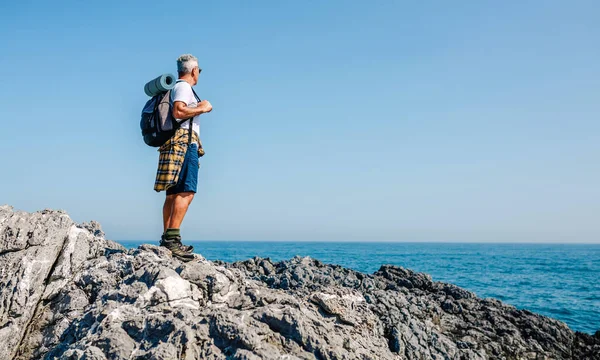 シニア男でバックパックハイキング海の風景を見て — ストック写真