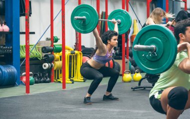 Spor salonunda ağırlık kaldırmaya çalışan bir kadın.