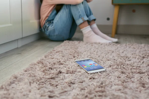 Telemóvel Deitado Chão Com Uma Menina Triste Irreconhecível Sentada Atrás — Fotografia de Stock