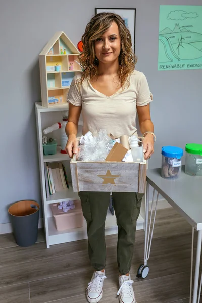 带着一盒废物在生态教室里循环利用的微笑女教师的画像 — 图库照片
