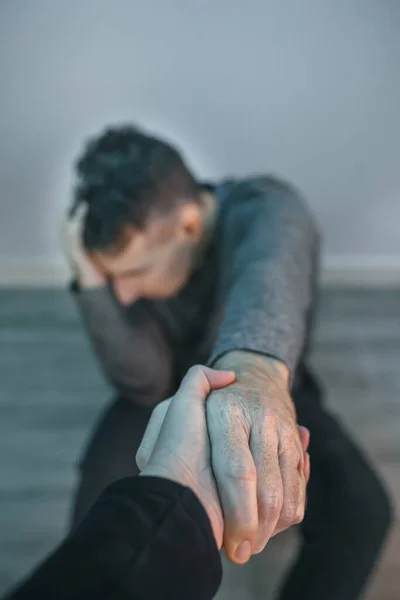 Unrecognizable man with problems receiving help from woman holding her hand. Helping hand concept