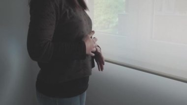 Oda penceresinin yanında kriz anksiyetesi yaşayan tanınmayan bir kadın.