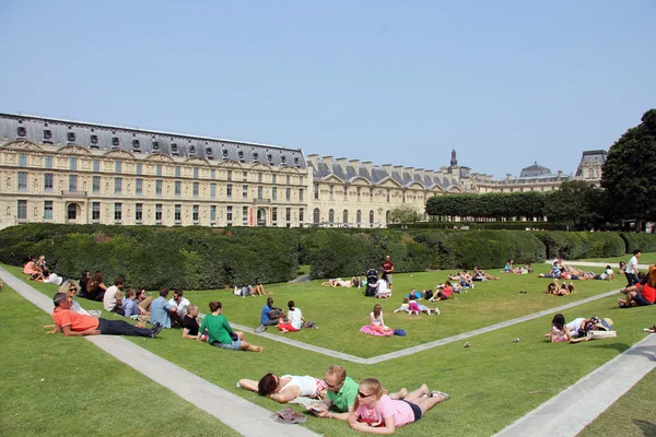 Menschen entspannen sich im Gras in der Nähe des Louvre-Museums in Paris — Stockfoto
