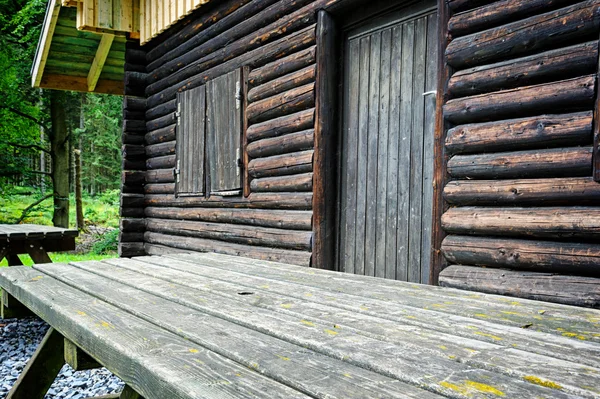 Mesa de madeira para piquenique ao lado da casa de campo da floresta — Fotografia de Stock