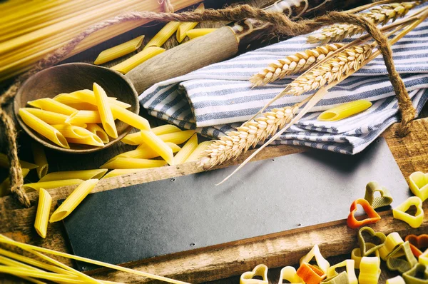 Houten bord met pasta assortiment — Stockfoto