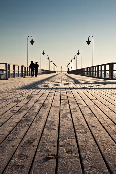 Salida del sol sobre el muelle a la orilla del mar — Foto de Stock