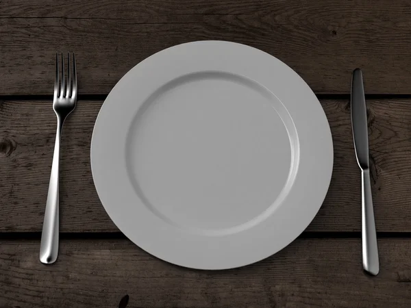 Piatto bianco, coltello e forchetta sul tavolo di legno — Foto Stock
