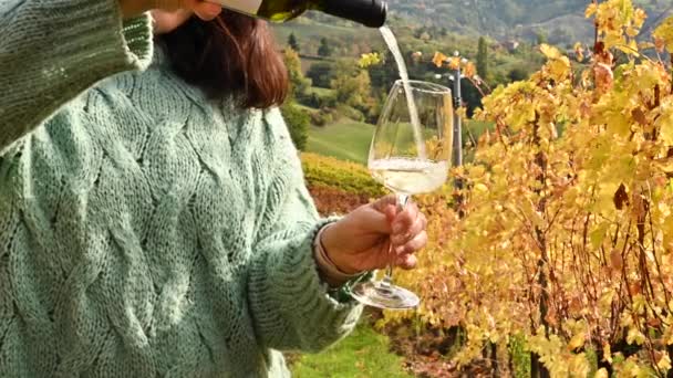 Flaska och glas vin i kvinnliga händer. Personen häller vinäger a i bergen i Italien. Gyllene vingårdar på hösten. Italien. Toscana — Stockvideo