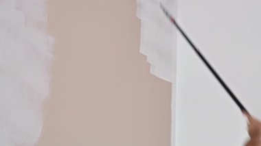 Ressam duvarı boyar. Boya silindirinin yakın plan görüntüsü