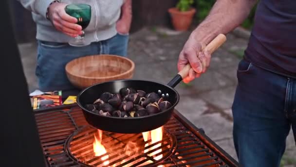 Pieczone kasztany i maroni nad ogniem na specjalnej stalowej patelni. Tradycyjne włoskie jesienne przysmaki — Wideo stockowe
